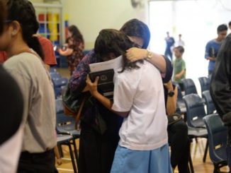 Hugging each other in relief that they won't be around for the new PSLE changes. (Asia One)
